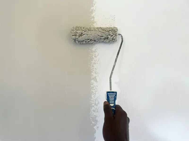 Rolo de pintura a aplicar tinta branca numa parede