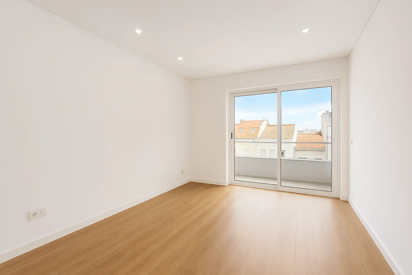 Sala de apartamento remodelado com pavimento de madeira e janela de sacada